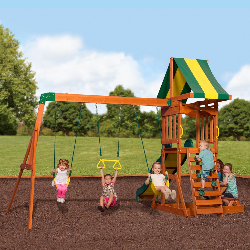 Sunnydale Cedar Swing Set in a garden, showing the swing beam, covered deck and rock wall ladder